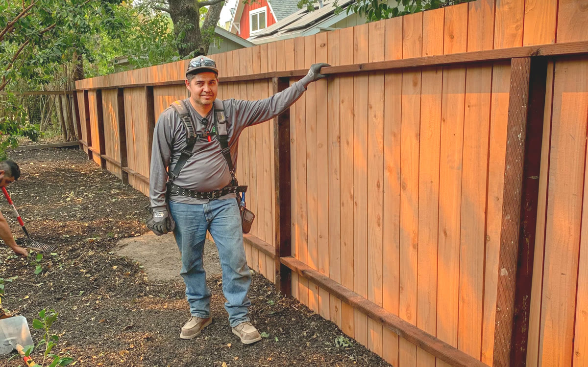 Roberto Gonzalez of Golden Grove Landscape beside a newly built redwood fence